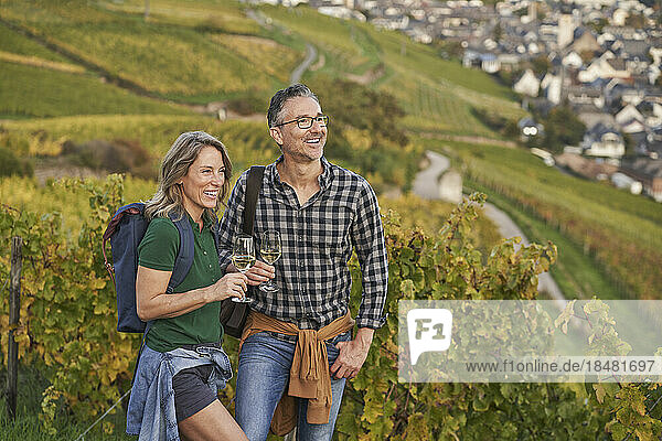 Happy man and woman standing with wineglasses on hill