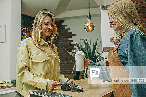 Smiling customer paying via tap to pay at coffee shop