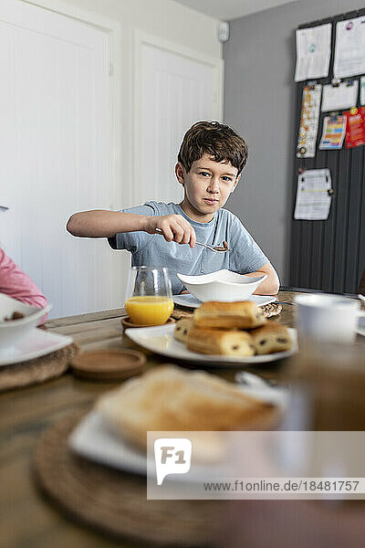 Boy having breakfast at table at home