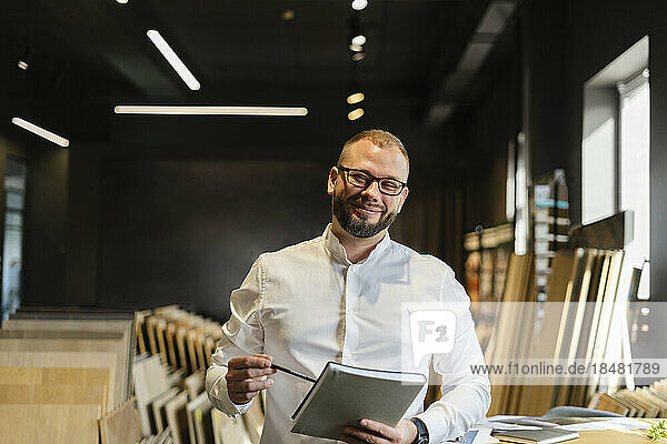 Portrait of smiling businessman holding book in architect's office