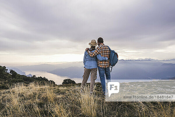 Loving couple standing with arms crossed on mountain