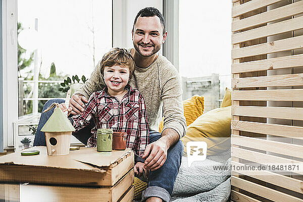 Smiling father and son with model house at home