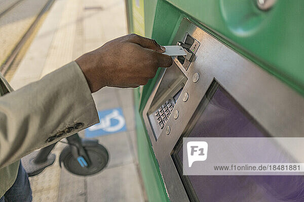 Hand eines Geschäftsmannes  der eine Karte in einen Geldautomaten einführt