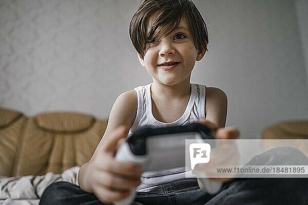 Happy boy with controller playing video games at home