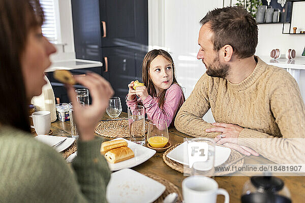 Mädchen frühstückt mit der Familie zu Hause