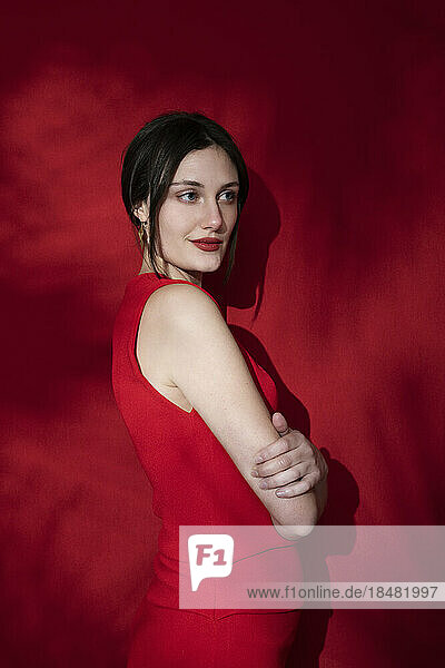 Thoughtful woman standing against red background