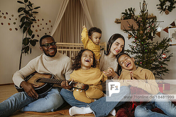 Cheerful family spending time together at Christmas playing the guitar