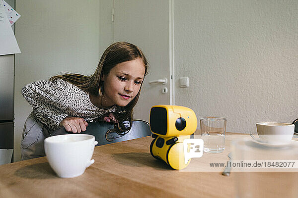 Curious girl looking at robotic model on table in home
