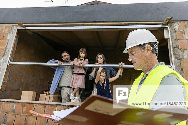 Contractor with family seen through window at construction site