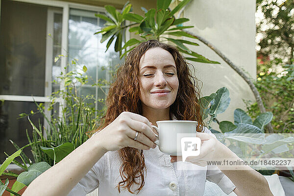 Lächelnde Frau genießt eine Tasse Tee im Hinterhof