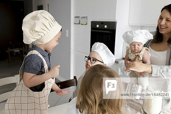 Children having fun preparing dough in kitchen