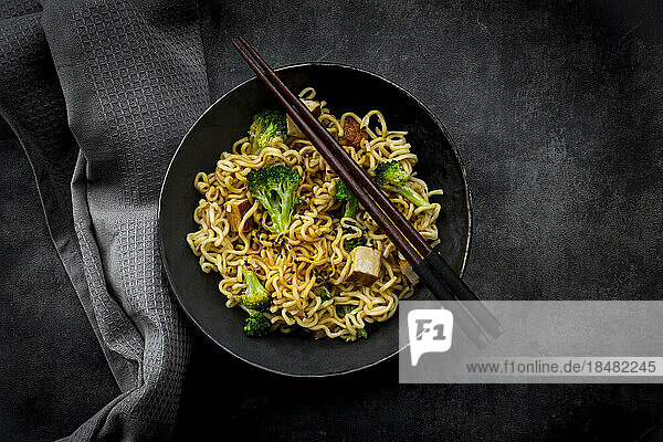 Studio shot of plate of ready-to-eat vegan noodles with broccoli  tofu and soy sauce