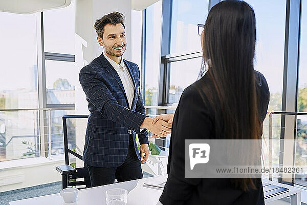 Smiling recruiter doing handshake with candidate after interview at office