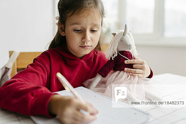 Mädchen mit Einhornspielzeug lernt zu Hause