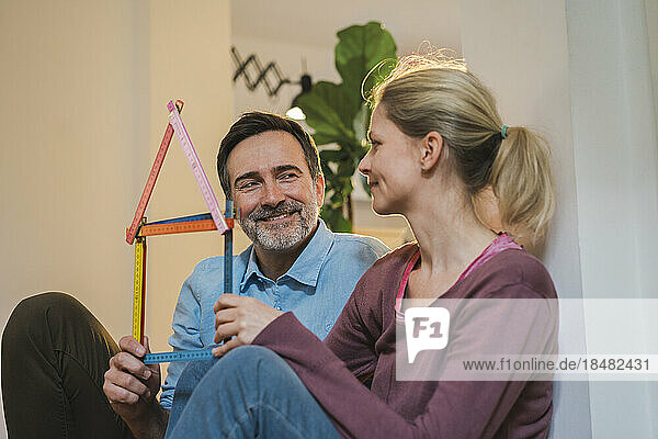 Couple holding house model made from folding ruler at home