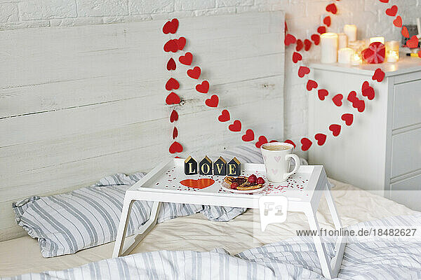 Frühstückstablett mit herzförmiger Dekoration im Schlafzimmer zu Hause