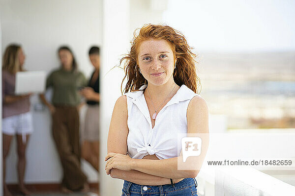 Confident redheaded businesswoman standing with arms crossed