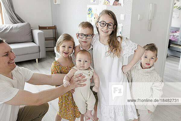 Father and children standing together in living room at home