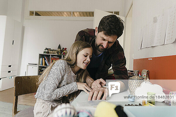 Vater zeigt Tochter  die zu Hause sitzt  eine Smartwatch
