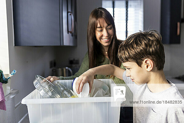 Happy woman with boy recycling plastic bottles at home