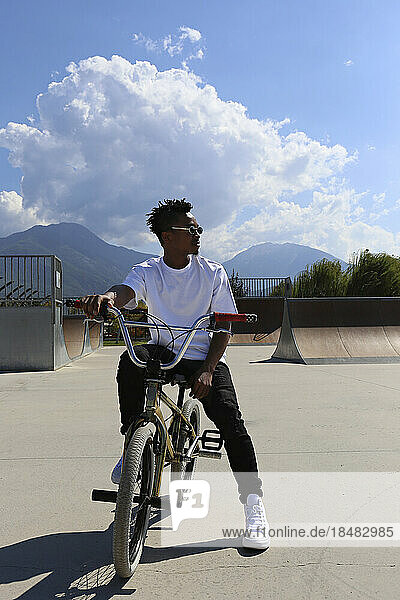 Young man sitting on BMX bike at skatepark