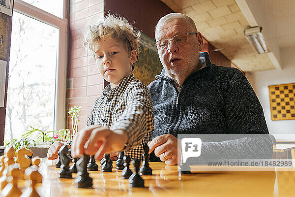 Son playing chess with grandfather at club