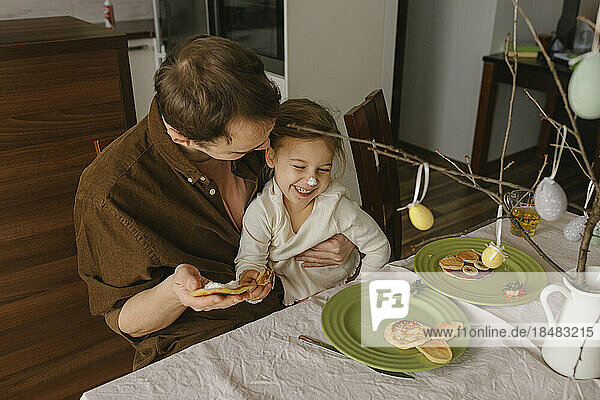 Playful father with daughter enjoying having pancakes for breakfast at home