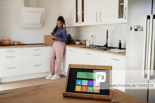 Hausautomations-App auf Tablet-PC mit Frau im Hintergrund
