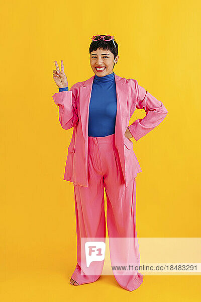 Happy woman wearing blazer gesturing over yellow background