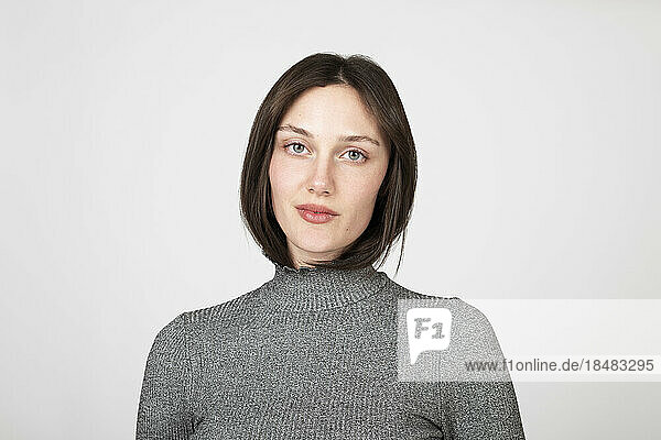 Confident young woman wearing turtleneck against white background
