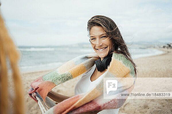 Happy woman with scarf and headphones enjoying at beach