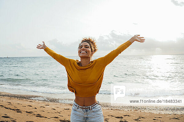Happy woman with arms outstretched enjoying at beach