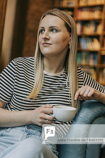 Contemplative woman sitting with coffee cup in cafe