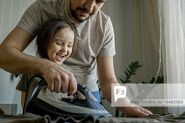 Glücklicher Junge hilft Vater beim Bügeln von Kleidung zu Hause