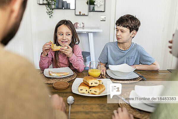 Happy siblings with mother and father having breakfast together at home