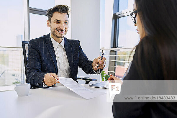 Recruiter taking signature of candidate on form after interview at office