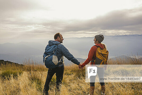 Happy mature man and woman holding hands on mountain
