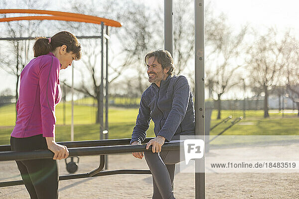 Mature couple exercising on parallel bars in park