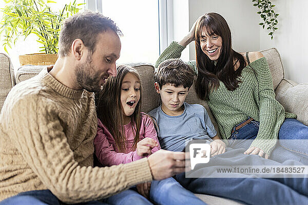 Happy family using smart phone on sofa at home