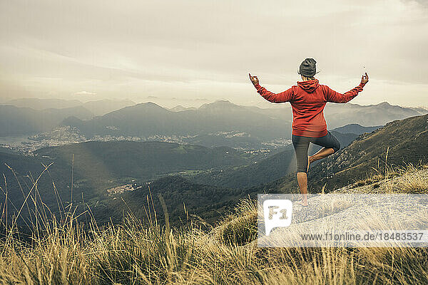 Mature woman practicing yoga on mountain