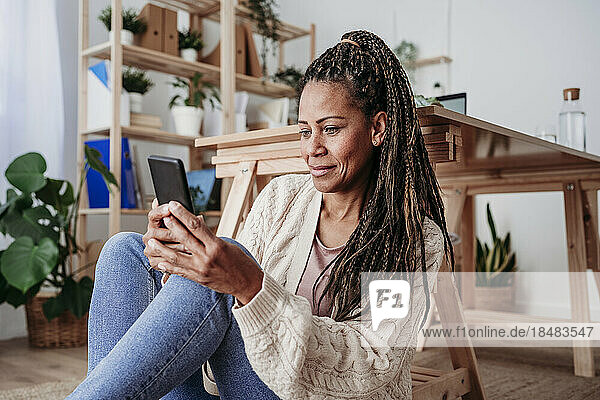 Smiling woman using smart phone at home