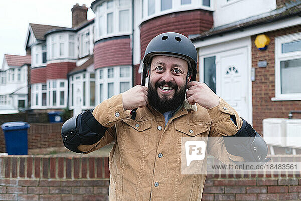 Happy man adjusting helmet outside building