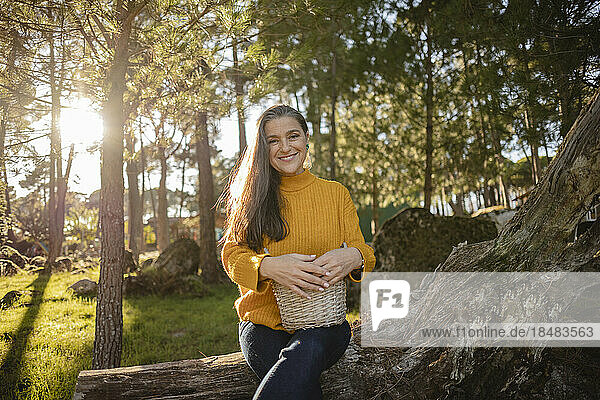 Smiling mature woman holding a wicker basket in nature