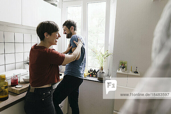 Mature couple enjoying in kitchen at home