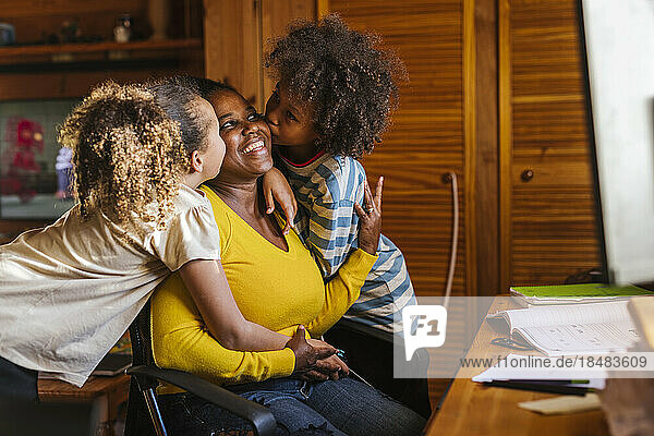 Sohn und Tochter küssen Mutter  die zu Hause sitzt