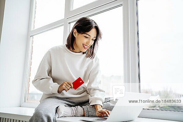Happy woman making payment with credit card on laptop