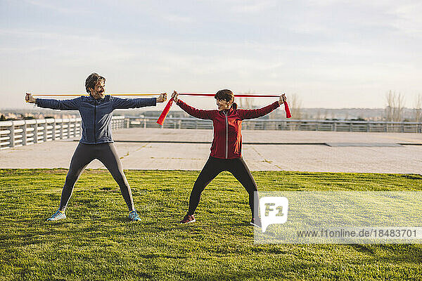 Happy mature couple exercising with resistance bands in park