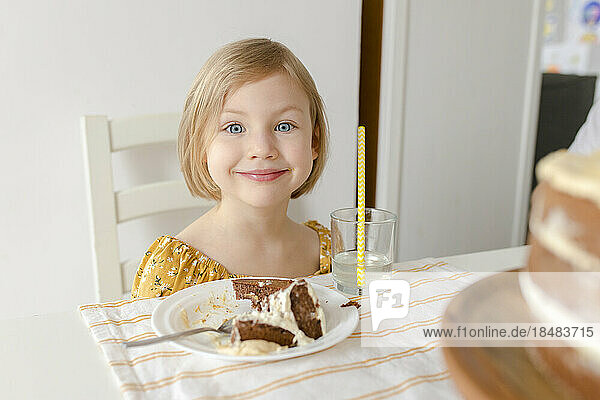 Smiling girl sitting at table with cake
