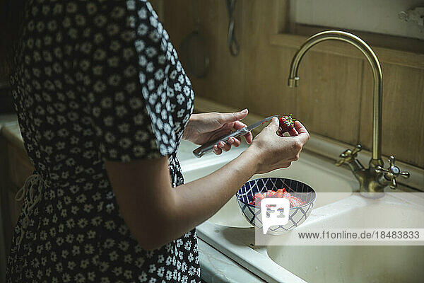 Hands of woman cutting fresh strawberries in kitchen