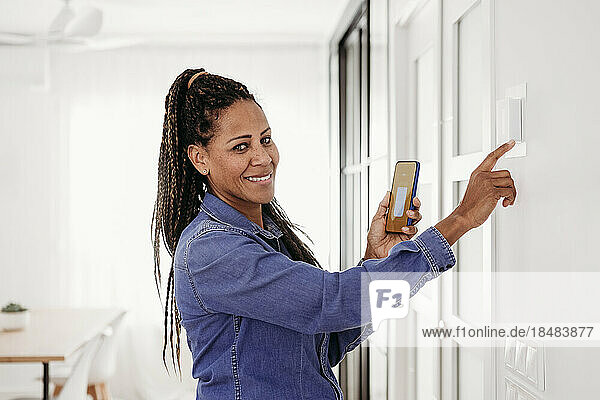 Happy mature woman adjusting thermostat through smart phone app